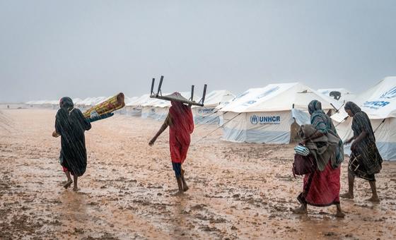 Displaced women carry their belongings through a flooded gathering site near Kassala, Sudan.