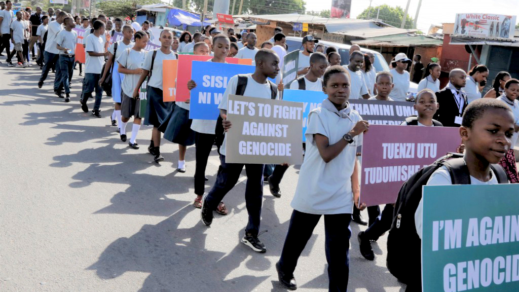 Photo: UNIC Dar Es Salaam People march holding signs protesting against genocide