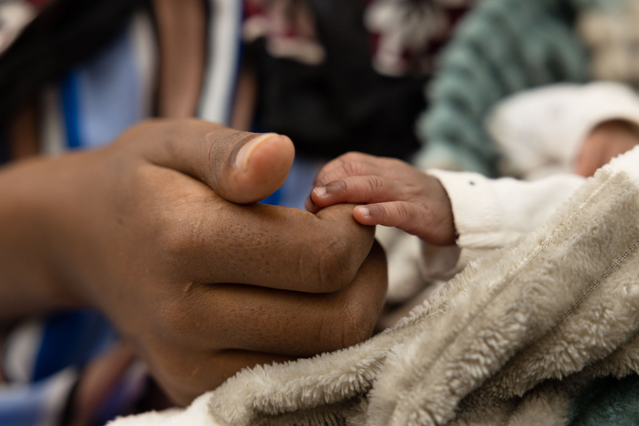 A young woman holding her newborn hand.