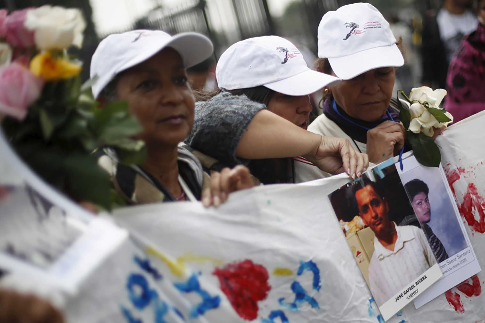 A group of women demonstrating and showing photos of disappeared migrants.