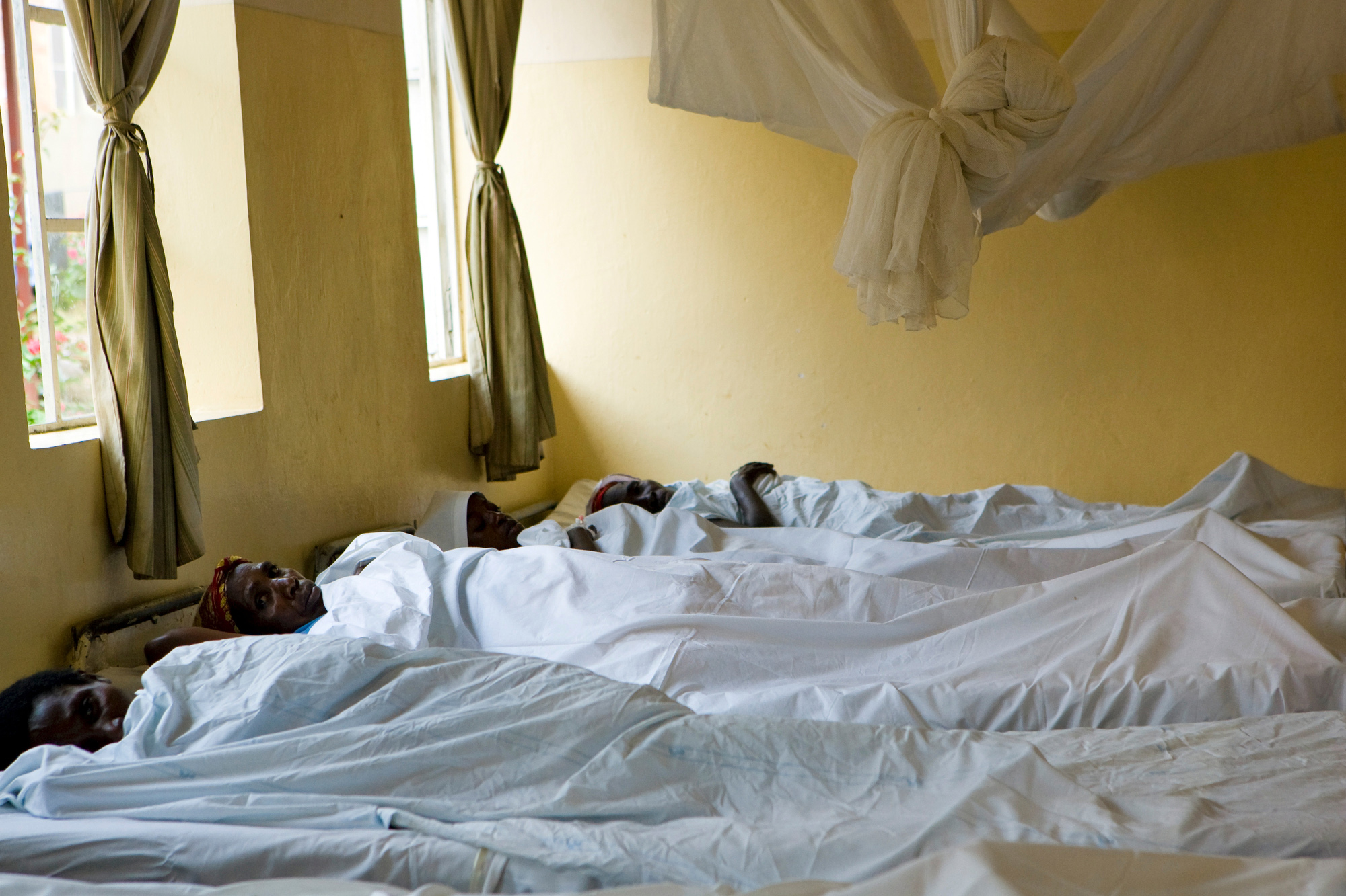 A group of women victims of sexual violence lie on beds being treated in a hospital.