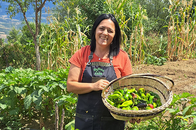 smiling woman holding basket of peppers