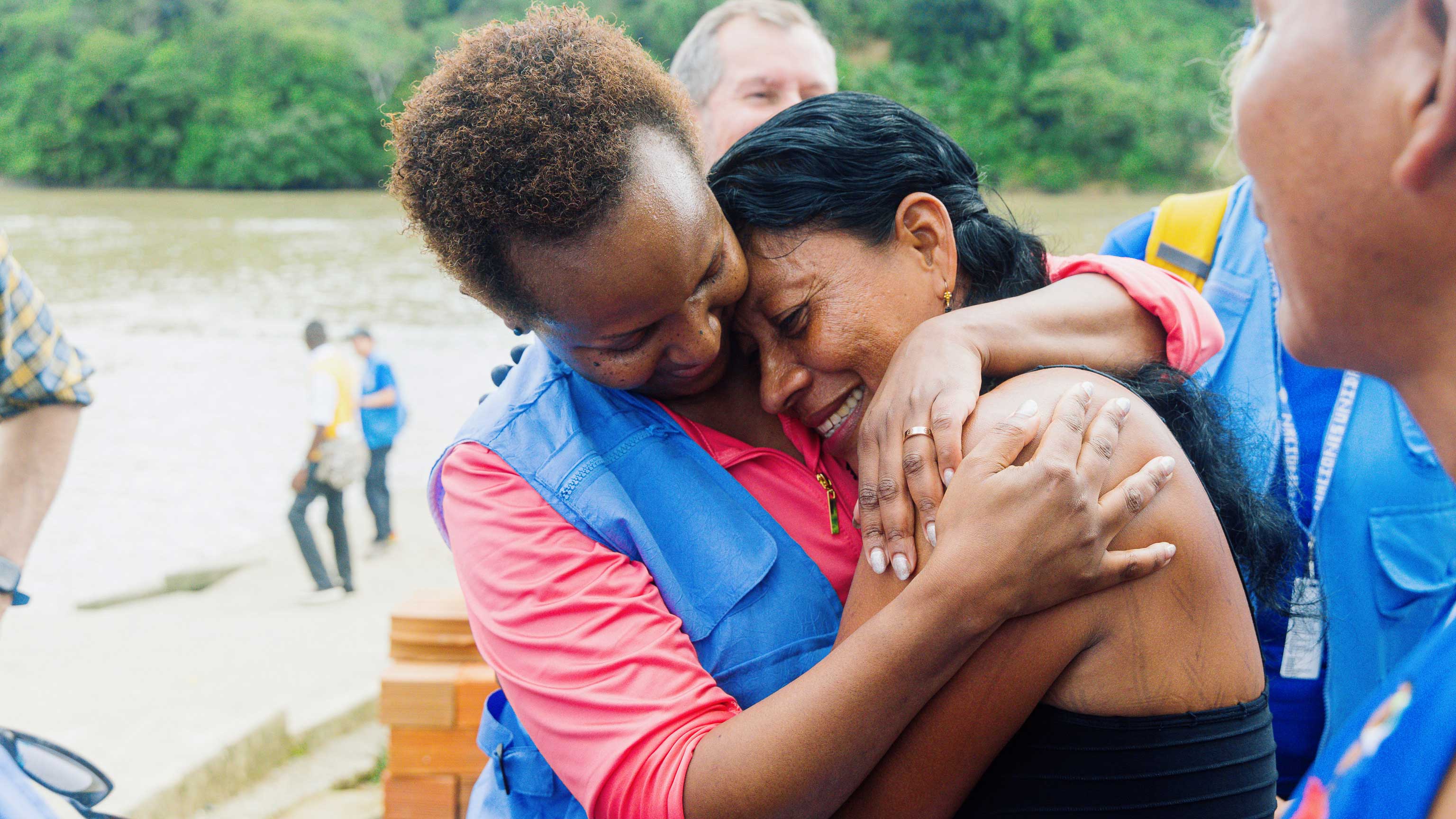 Msuya hugs a woman who has indigenous tatoos on her arm