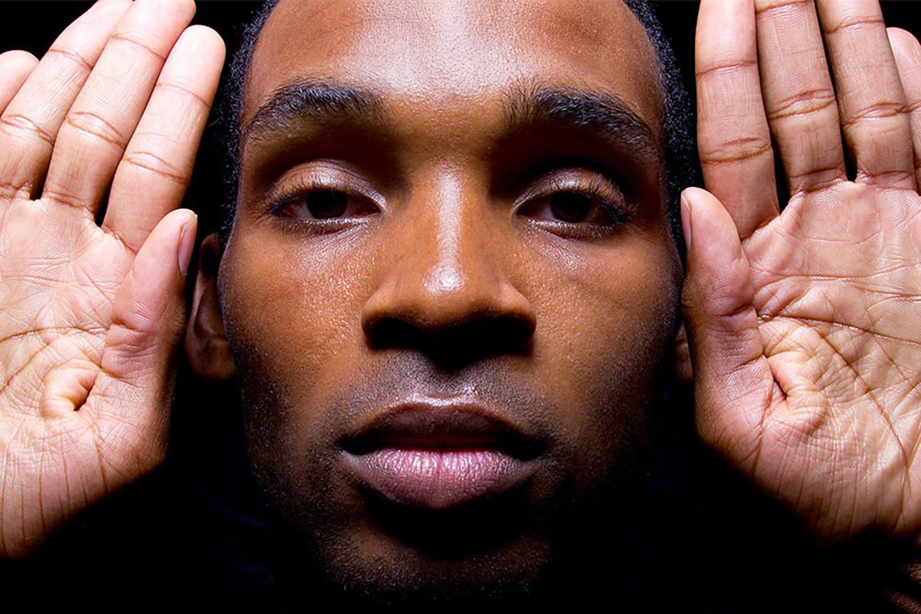 Close-up of a man with the palms of his hands next to his head.